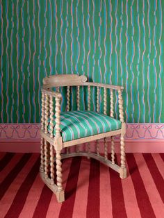 a wooden chair sitting on top of a red and green striped floor next to a wall