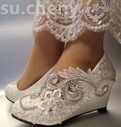 a woman's white wedding shoes with beading on the heel and lace detailing