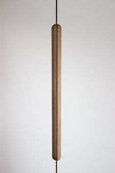 a tall wooden object hanging from a metal hook on a white wall in a room