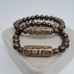 Agate Tibetan Dzi bead bracelet with Bronzite stone. Lucky amulet for a gift. Bracelet size made to order. Please send me the size of your wrist so the bracelet will fit perfectly. Bead size: Dzi - 3×1 cm/1.16×0.42 inches. Bronzite - 8 mm/0.3 inches. If you choose to pack No.2, leave me a message about which stamp you would like (Crown, Cloverleaf, Just Smile). I will choose the color of the stamp at my discretion if you do not have any other wishes 🙂 You may also want to see other Tibetan Dzi Tibetan Bracelet Buddha Groove, Symbolic Beaded Bracelets With Natural Stones For Meditation, Agate Bracelets With 108 Beads For Meditation, Agate Meditation Bracelets With 108 Beads, Traditional Brown Beaded Bracelets With Natural Stones, Traditional Brown Beaded Bracelet With Natural Stones, Spiritual Healing Brown Beads, Symbolic Beaded Bracelets With Natural Round Beads, Symbolic Natural Stone Beaded Bracelets With Round Beads