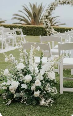 an outdoor ceremony setup with white flowers and greenery on the grass in front of chairs