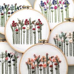 four embroidery hoops with flowers on them, each embroidered in different colors and sizes