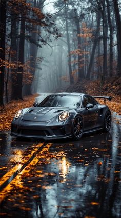 a black sports car parked on the side of a wet road with trees in the background