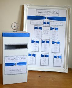 a blue and white wedding seating chart next to a box with a ring on it