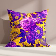 a yellow and purple floral pillow sitting on top of a white shelf next to a gray wall