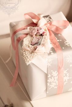 a white gift box with pink ribbon and flowers