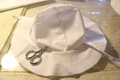 a pair of scissors sitting on top of a white hat