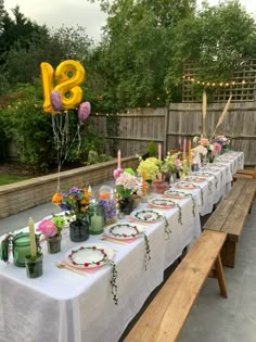 a long table is set up with flowers and candles for an outdoor party or celebration