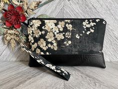 "An exterior zipper pocket can be added for an additional cost. This cute wristlet wallet is the perfect go to alternative to our everyday handbags! It will hold all your necessities including credit cards, ID and your smartphone. Super convenient for the mom on the go!! This sleek and contemporary wristlet clutch was designed using a heavy weight black fabric with a floral design. It has a black vegan leather base and a detachable strap. The well organized interior is a solid black fabric that Black Rectangular Wristlet For Gift, Rectangular Black Wristlet For Gift, Rectangular Black Wristlet As A Gift, Pouch Wristlet As Gift, Black Wristlet With Cell Phone Pocket For Gift, Black Wristlet With Cell Phone Pocket As Gift, Pouch Wristlet With Wrist Strap As Gift, Wristlet Pouch With Wrist Strap As Gift, Gift Clutch Wristlet With Wrist Strap