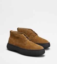 Characterized by a chunky but at the same time sober and refined outsole, the Tod's W. G. style is here proposed in desert boot version. Crafted in suede, with iconic rubber pebbles on the bottom and heel, they are enhanced by Tod's monogram stamped on the front. Formal Boots With Contrast Sole And Plain Toe, Modern Leather Shoes With Textured Sole And Round Toe, Classic Moc Toe Boots With Contrast Sole, Classic Boots With Moc Toe And Contrast Sole, Calf Leather Boots With Contrast Sole And Plain Toe, Leather Walking Shoes With Round Toe And Contrast Sole, Leather Shoes With Contrast Sole For Walking, Brown Calf Leather Boots With Textured Sole, Leather Desert Boots With Lug Sole And Round Toe