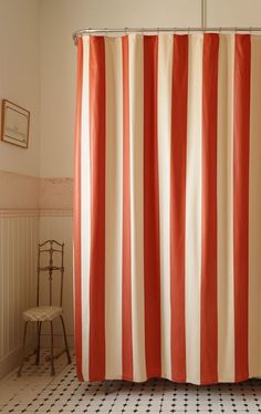 an orange and white striped shower curtain in a bathroom with black and white floor tiles