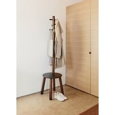 a pair of shoes is sitting on a stool next to a coat rack and closet