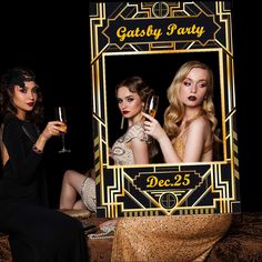 two women sitting on a bed holding wine glasses in front of a gatsby party sign