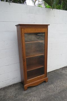 an old wooden bookcase sitting against a white brick wall next to a cement floor