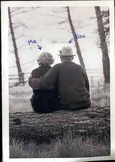 an old photo of two people sitting on a log looking at the woods and trees