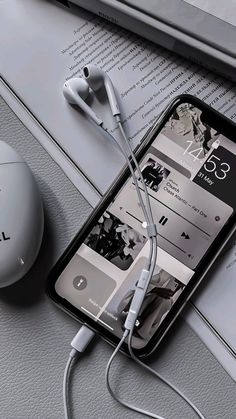 an iphone with ear buds connected to it next to a computer mouse and headphones