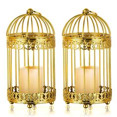 two golden birdcages with candles in them sitting next to each other on a white surface