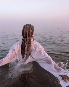 a woman sitting on top of a boat in the middle of the ocean with long hair