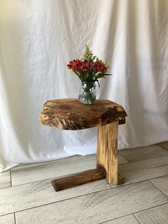 a vase filled with flowers sitting on top of a wooden table next to a white wall