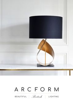 the arc form table lamp is shown in gold and black with a black shade on it