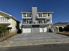 a two story house on the corner of a street with garages and balconies