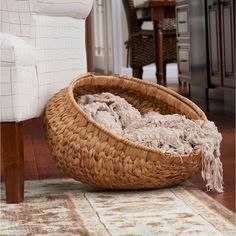 a large woven basket sitting on top of a wooden floor next to a white chair