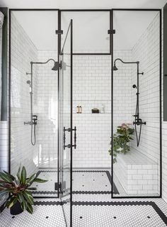 a black and white tiled bathroom with glass shower doors, potted plants on the floor