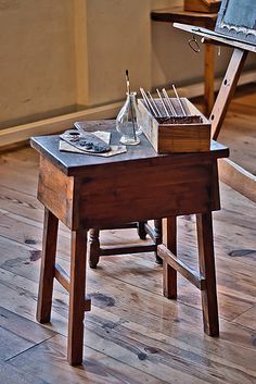 an old wooden desk and chair in a room with hard wood flooring on the ground