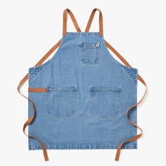 a blue denim apron with two straps on the front and back, hanging from an adjustable strap