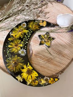 a plate with yellow flowers on it sitting on a table next to some dried grass