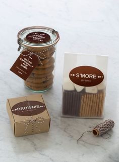 some cookies in a glass jar next to a package of brownie sticks and a box of s'mores