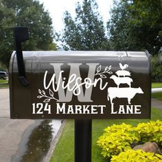 a mailbox with the word wisconsin on it in front of some flowers and trees