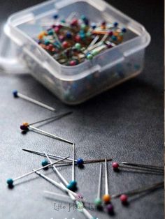 there are many pins and needles in the plastic container on the table next to each other