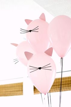 three pink balloons with cat heads on them