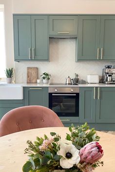 a vase with flowers sitting on top of a table in front of a stove and oven