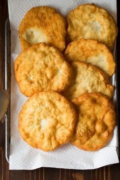 some biscuits are sitting on top of a white paper towel next to a fork and spoon