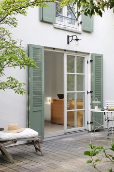 an outdoor patio with chairs, tables and green shutters