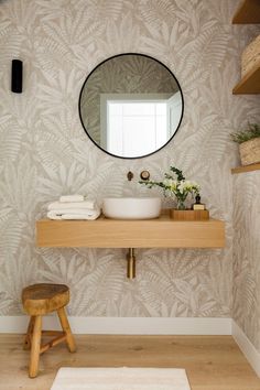 a bathroom with a sink, mirror and stool in front of the window on the wall