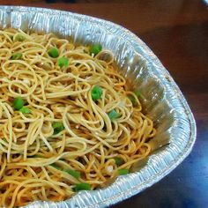 a metal pan filled with noodles and peas