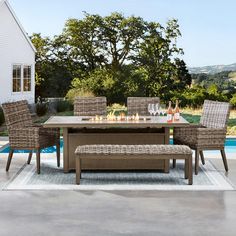 an outdoor dining table with four chairs and a bench next to a swimming pool in the background