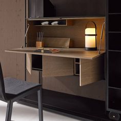 a desk with a lamp on top of it next to a chair and bookcase