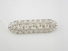 Vintage platinum diamond brooch. The brooch features five European and twenty-eight full cut diamonds. The diamonds weigh approximately 3.50 carats total and have F-H color and VS2-SI2 clarity. The brooch measures 2 inches by 9/16 inches and weighs 6.07dwt. The brooch features an openwork design with filigree and milgrain detailing. Diamond Brooch, Pin Brooch, Brooch Pin, Brooches, Diamond Cuts, Platinum, Diamonds, Chain, Color