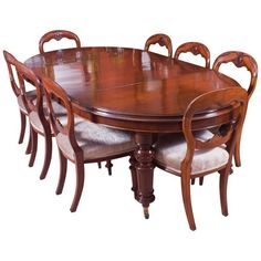 a wooden dining table with six chairs and a round centerpiece on one end, surrounded by white upholstered cushions