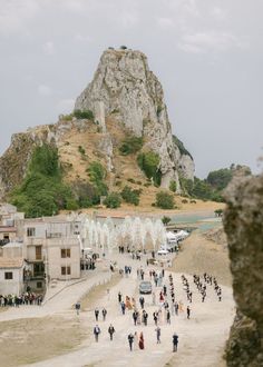 many people are walking around in front of a mountain