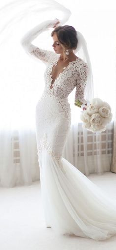 a woman in a wedding dress is posing with her arms behind her head and holding a bouquet