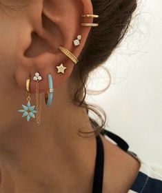 a woman wearing three different ear piercings with stars and chains on the side of her ear