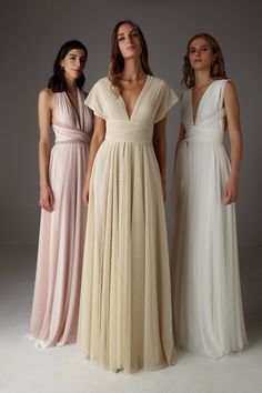 three women standing next to each other in long dresses with pleated details on the sides