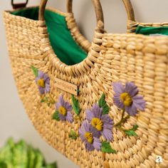 a wicker purse with flowers on it hanging from a wall next to lettuce