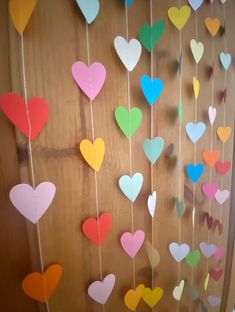 colorful paper hearts hanging from strings on a wooden door with string attached to it's sides