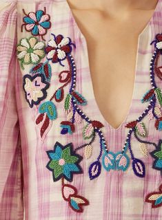 a close up of a woman wearing a pink shirt with flowers and leaves on it